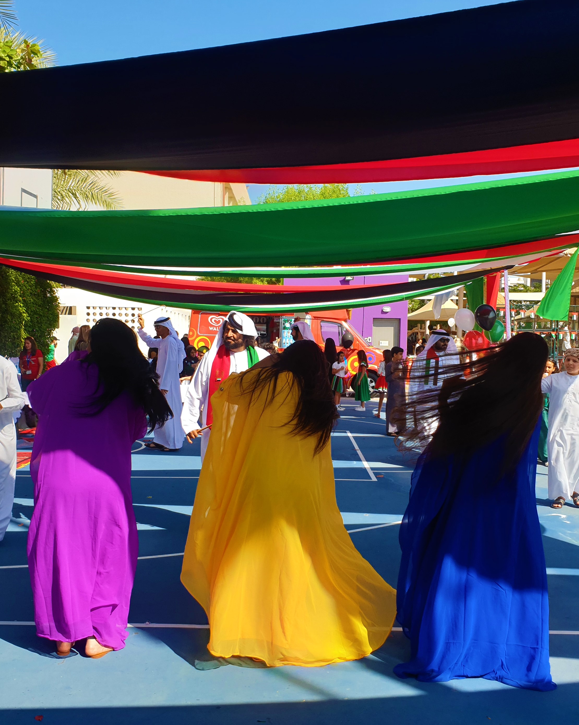 Wanita mengibaskan rambut mereka ke samping dan mengenakan pakaian tradisional berwarna cerah saat menampilkan tarian rakyat Emirat.