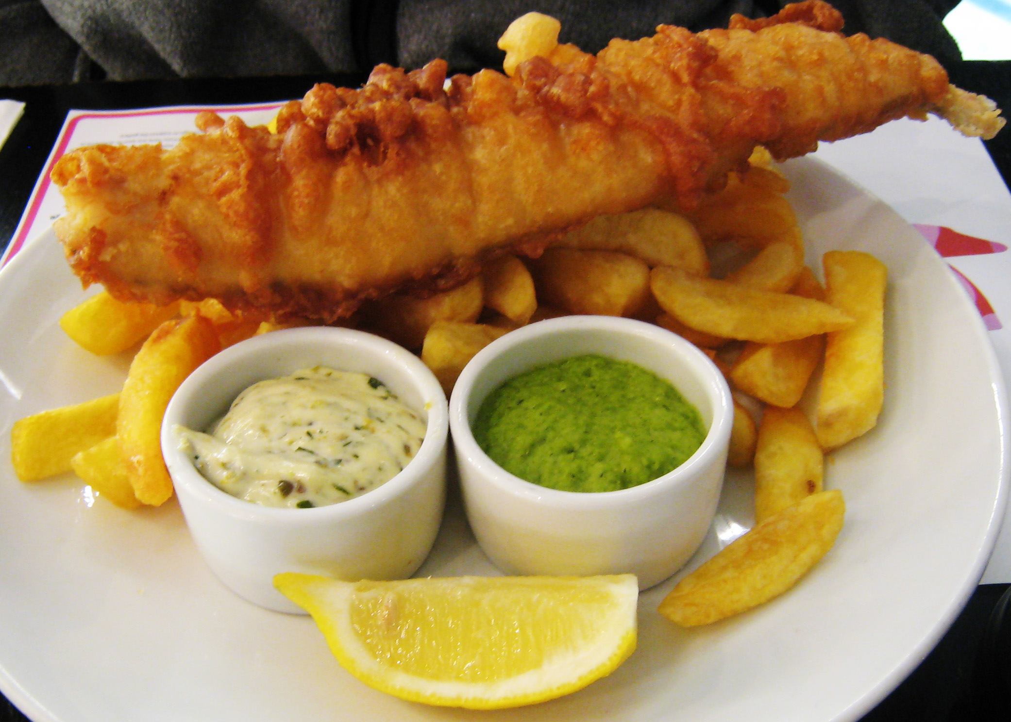 Fish and chips, a traditional British dish, served with lemon, tartar sauce and mushy peas