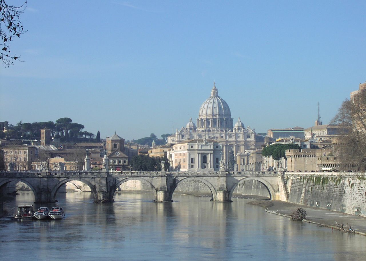 St. Peter's Basilica viewed from the Tiber River, with the Vatican Hill in the background and Castel Sant'Angelo to the right. Both the basilica and the hill are part of the sovereign state of Vatican City, the seat of the Holy See and the global center of the Catholic Church.