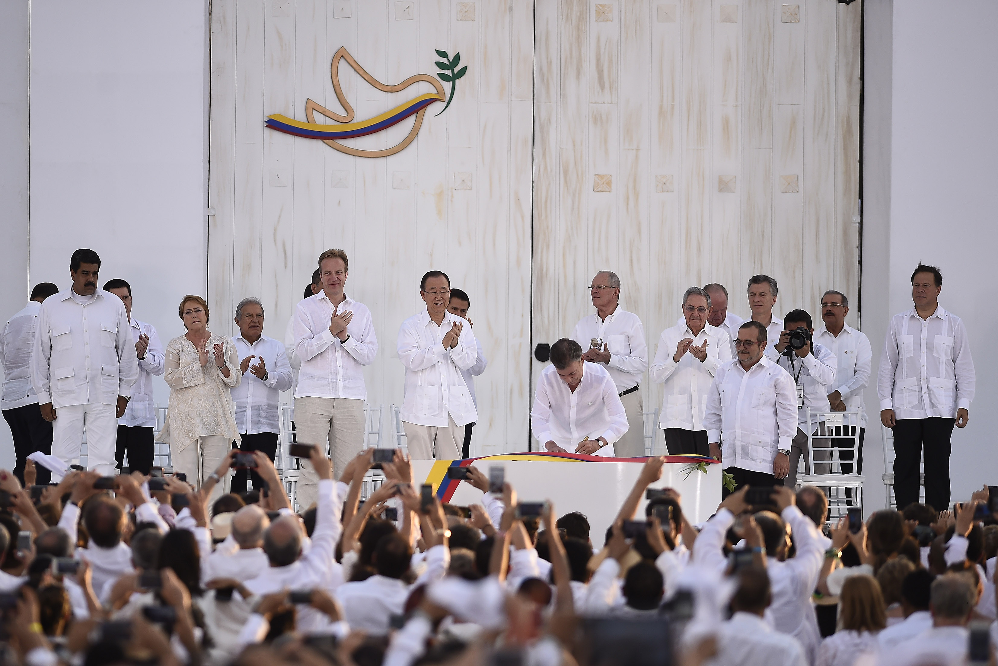 Former President Juan Manuel Santos signing a peace accord, a critical step towards ending decades of conflict with the FARC, though its implementation faces ongoing challenges and requires sustained efforts for national reconciliation and justice for victims.