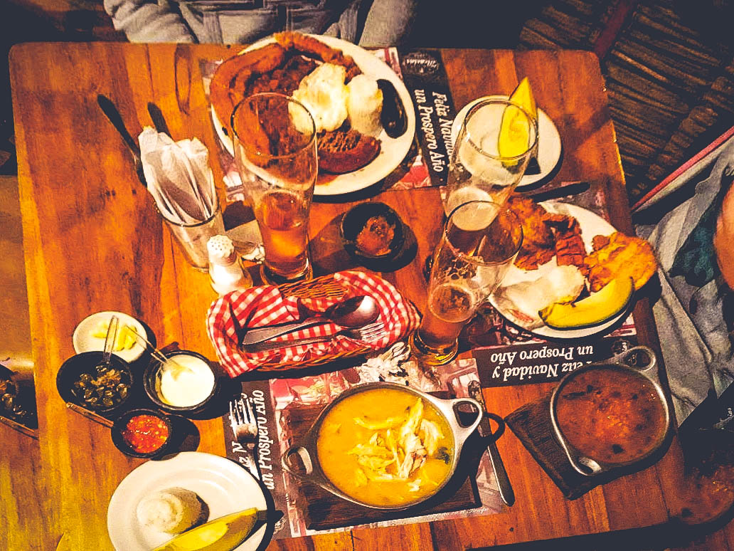 Bandeja paisa (top) and Ajiaco (bottom) are two iconic and traditional Colombian dishes. Bandeja paisa, from the Antioquia region, is a hearty platter reflecting a rural, working-class heritage, while Ajiaco, a Bogotá chicken and potato soup, showcases indigenous ingredients and criollo traditions, both representing the country's rich regional culinary diversity and cultural fusion.