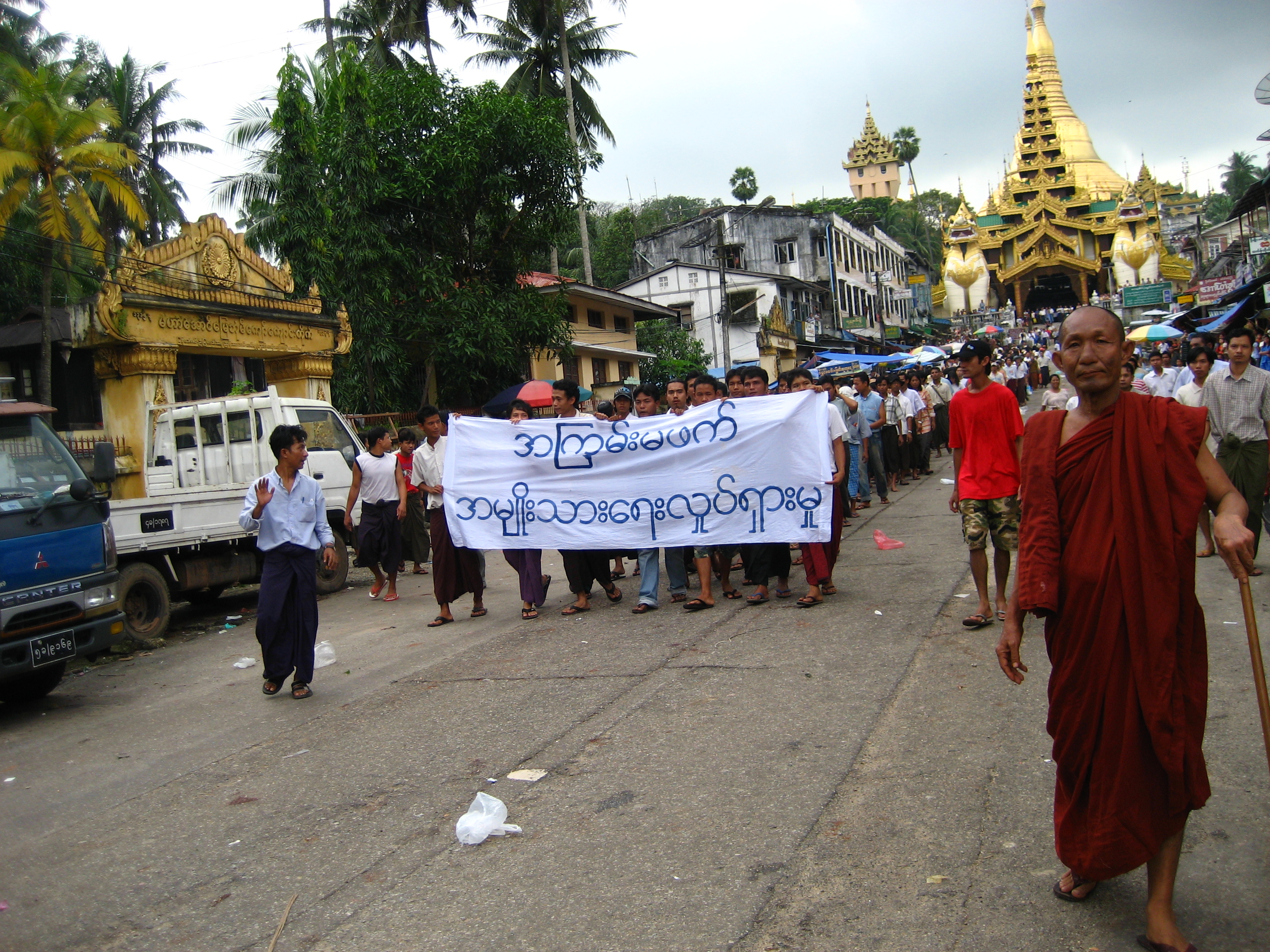 Những người biểu tình tại Yangon trong Cách mạng Nghệ Saffron 2007 với biểu ngữ ghi phi bạo lực: phong trào quốc gia bằng tiếng Miến. Phía sau là Chùa Shwedagon.