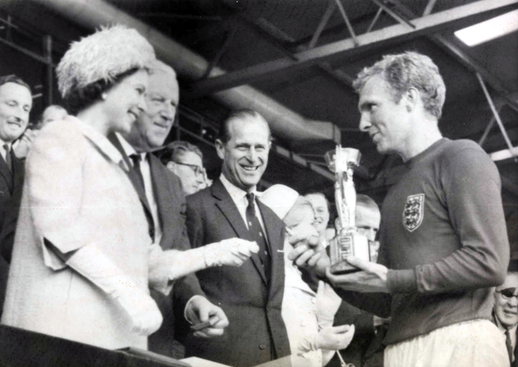 Ratu Elizabeth II menyerahkan trofi Piala Dunia FIFA 1966 kepada kapten England, Bobby Moore.