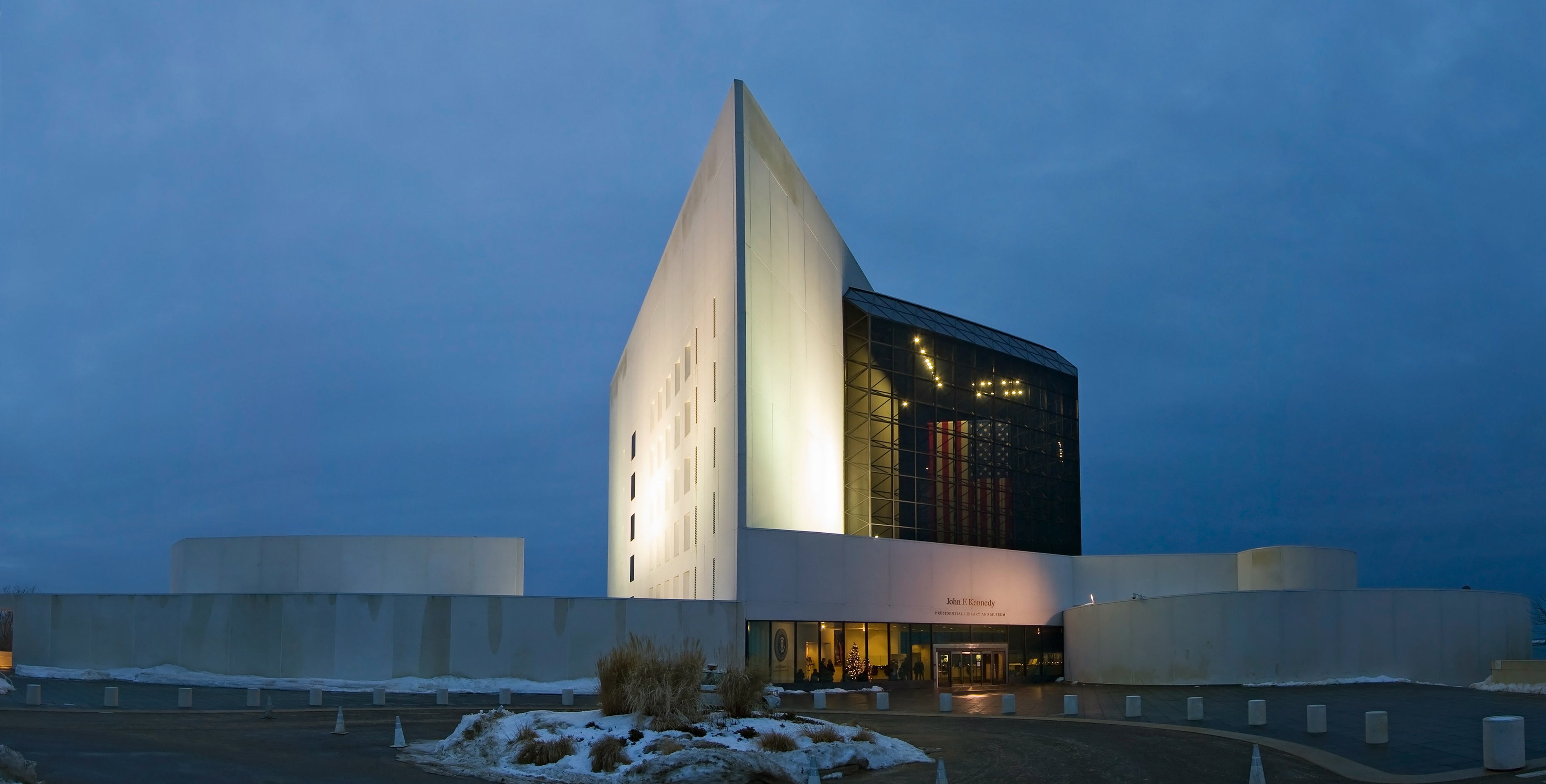 존 F. 케네디 도서관(John F. Kennedy Library)은 흰색 삼각형 타워로, 검은색 유리 건물 옆으로 솟아 있으며, 양쪽에 둥근 구조물이 있다.