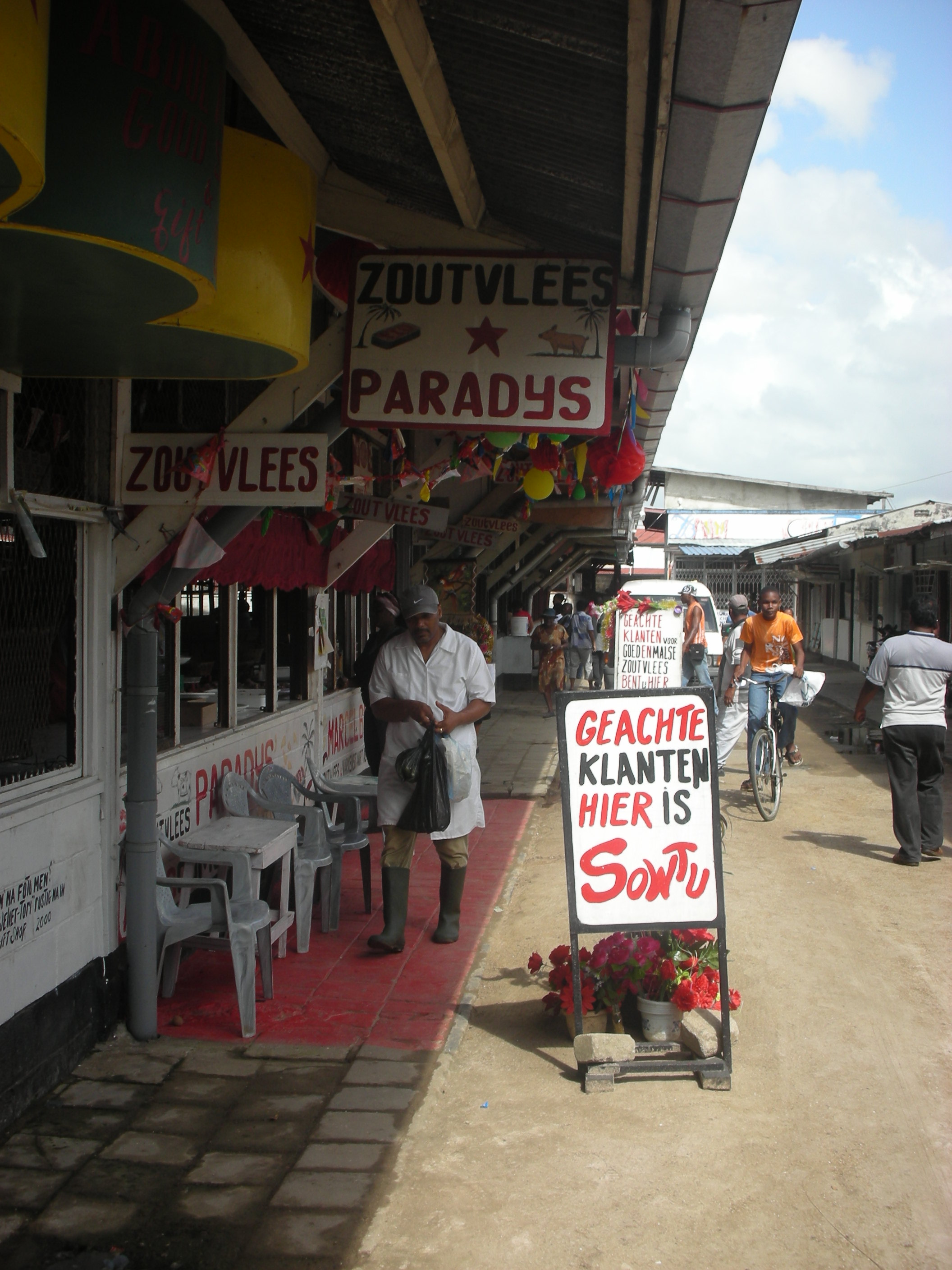 Penjual daging di Pasar Sentral di Paramaribo dengan papan nama yang ditulis dalam bahasa Belanda