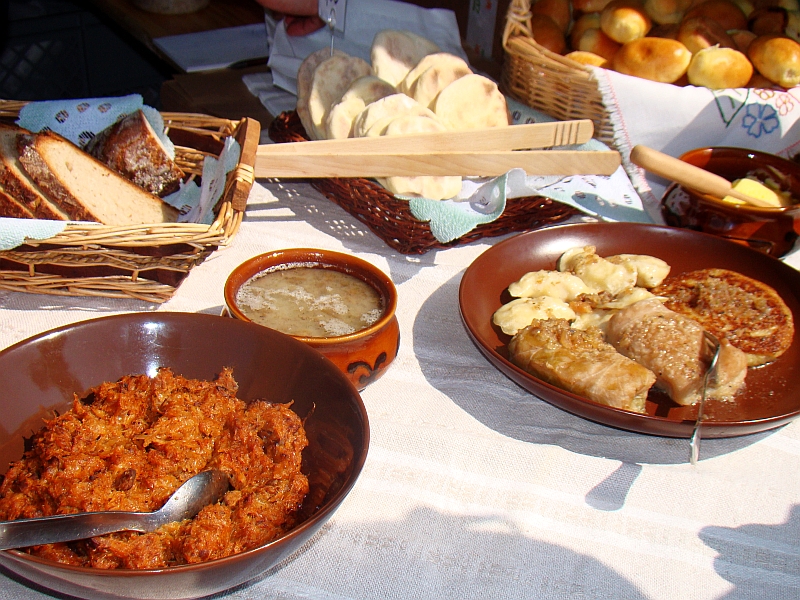 Selection of popular traditional dishes from Poland, including hunter's stew (bigos), stuffed cabbage rolls (gołąbki), rye soup (żurek), pierogi, potato pancakes, and rye bread