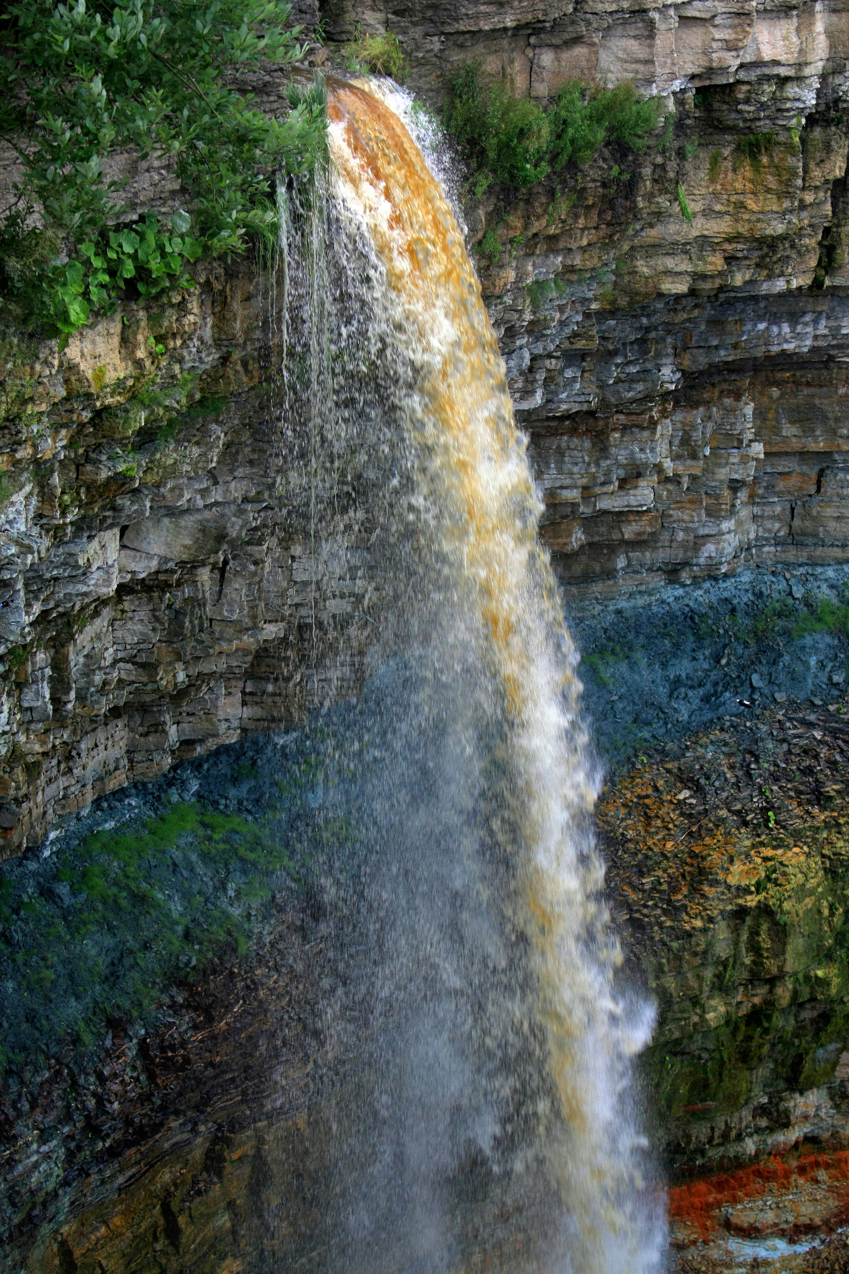 The cliff at Valaste Falls on the Ontika cliff, part of the Baltic Klint. This geological formation showcases layers of Ordovician and Cambrian limestone and sandstone, illustrating Estonia's ancient bedrock.