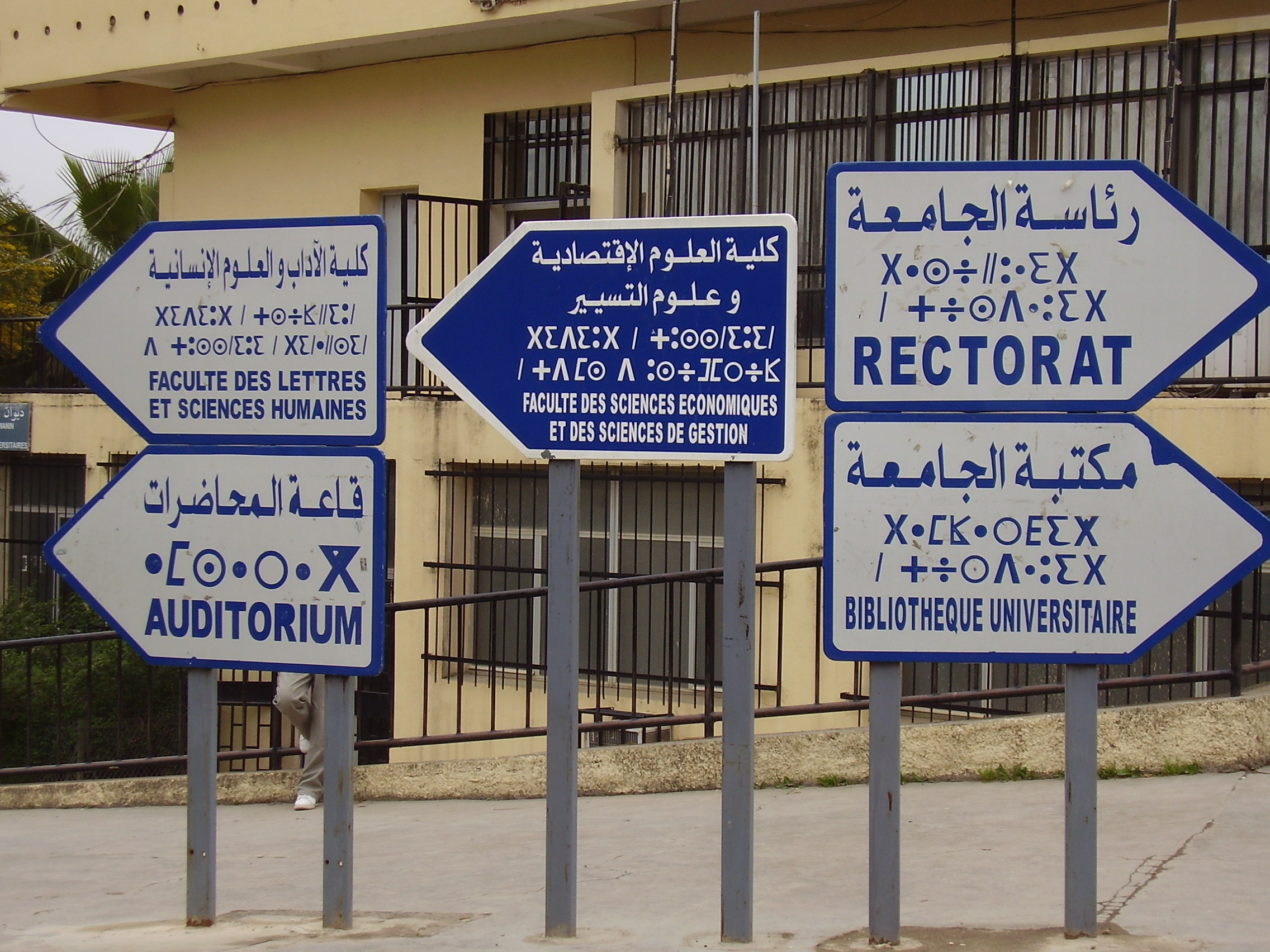 Papan tanda di Universitas Tizi Ouzou dalam tiga bahasa: Arab, Berber, dan Prancis