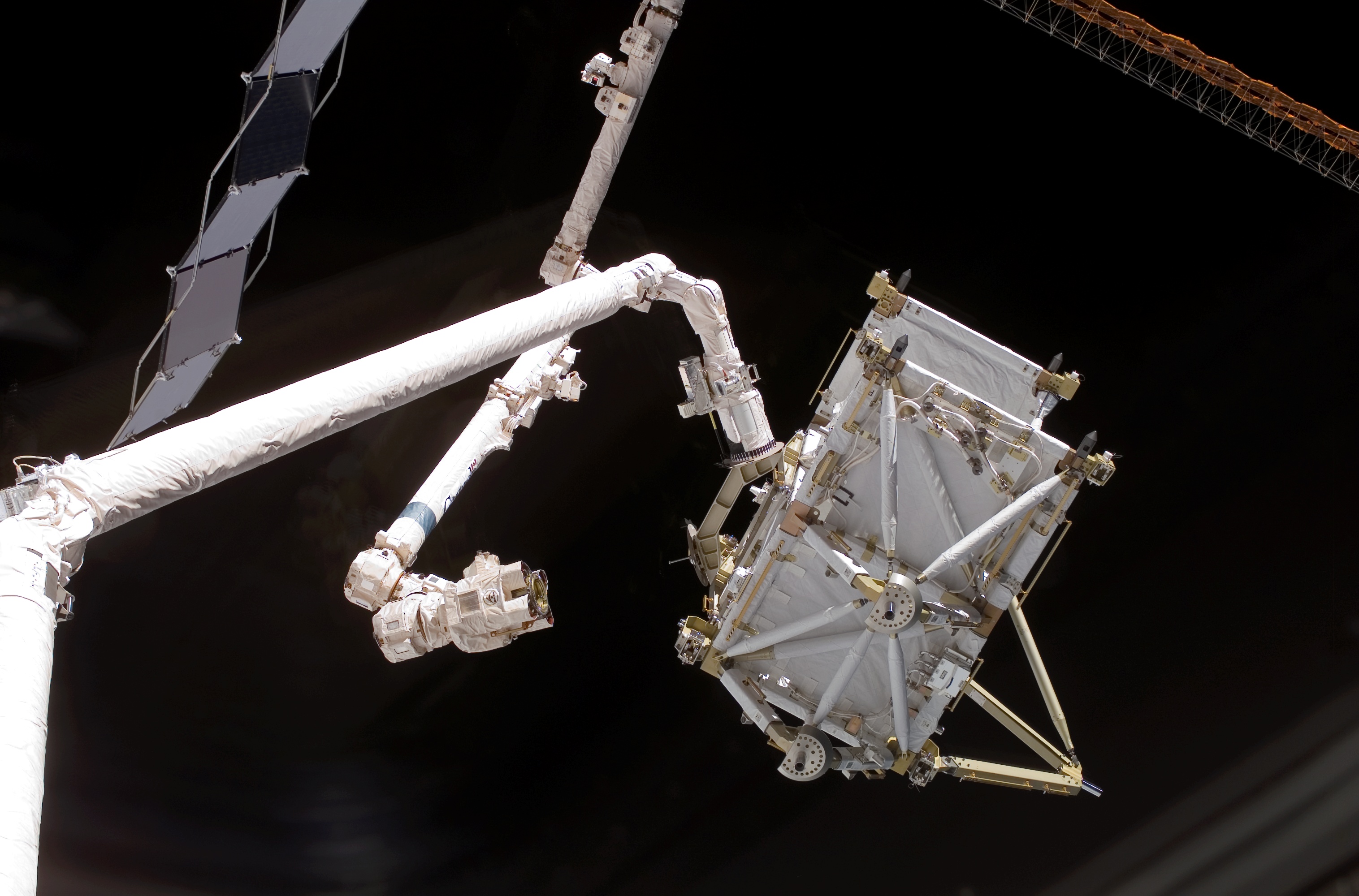 The Canadian-built Space Shuttle robotic arm (left), referred to as Canadarm, transferred the P5 truss segment over to the Canadian-built space station robotic arm, referred to as Canadarm2.
