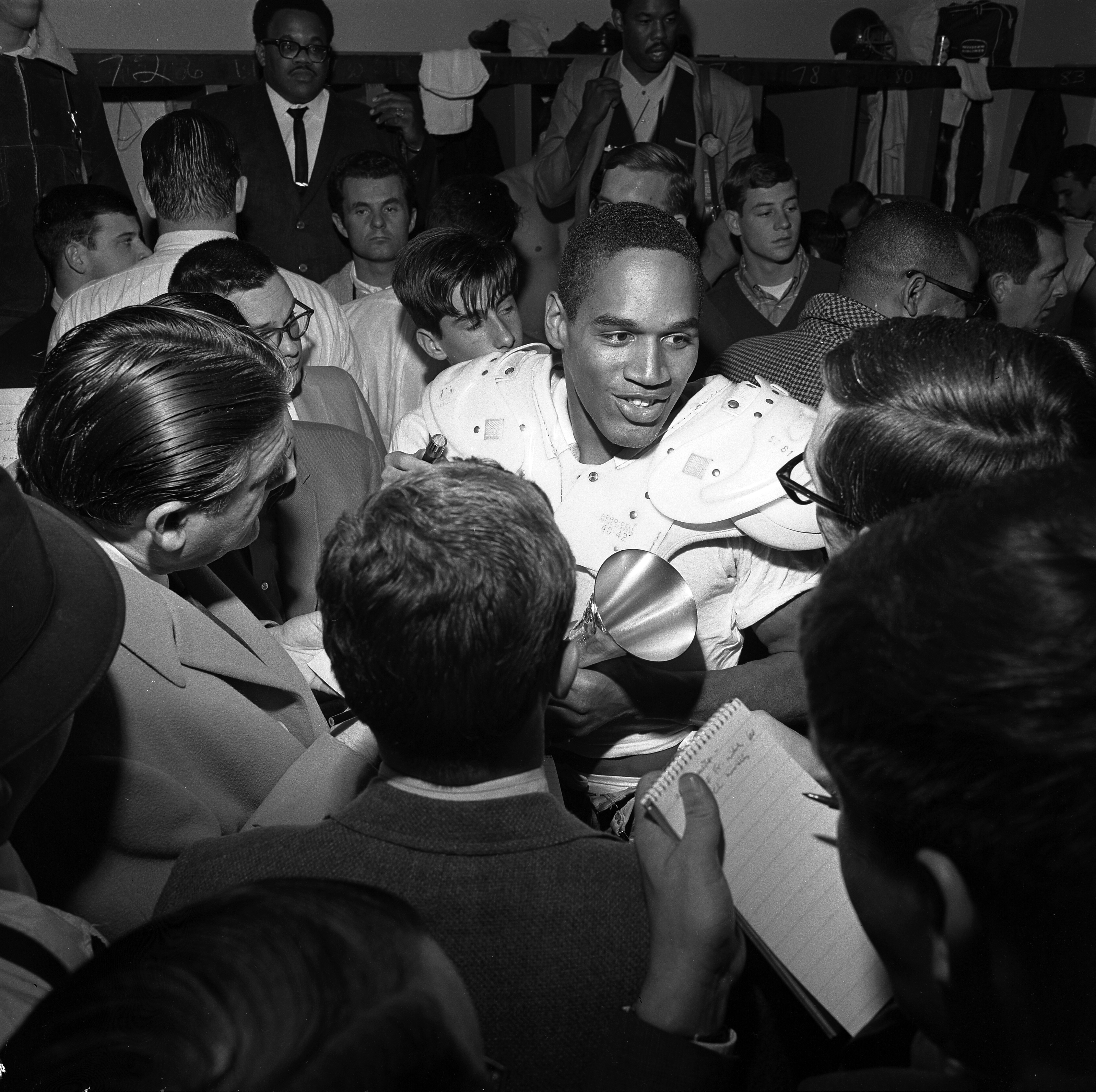 Simpson surrounded by reporters, smiling