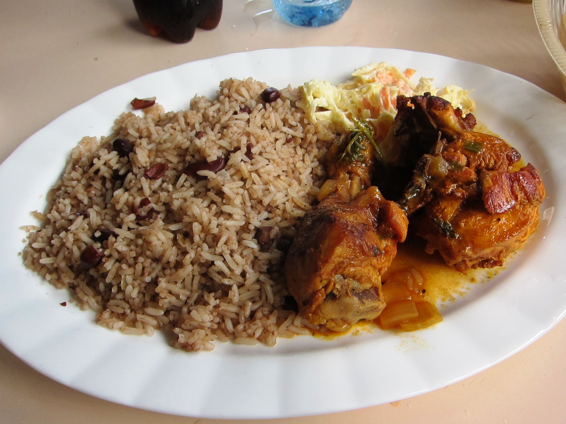 A classic Belizean meal: Rice and beans (often cooked with coconut milk), stewed chicken, and potato salad. This is a staple dish enjoyed across different ethnic groups.