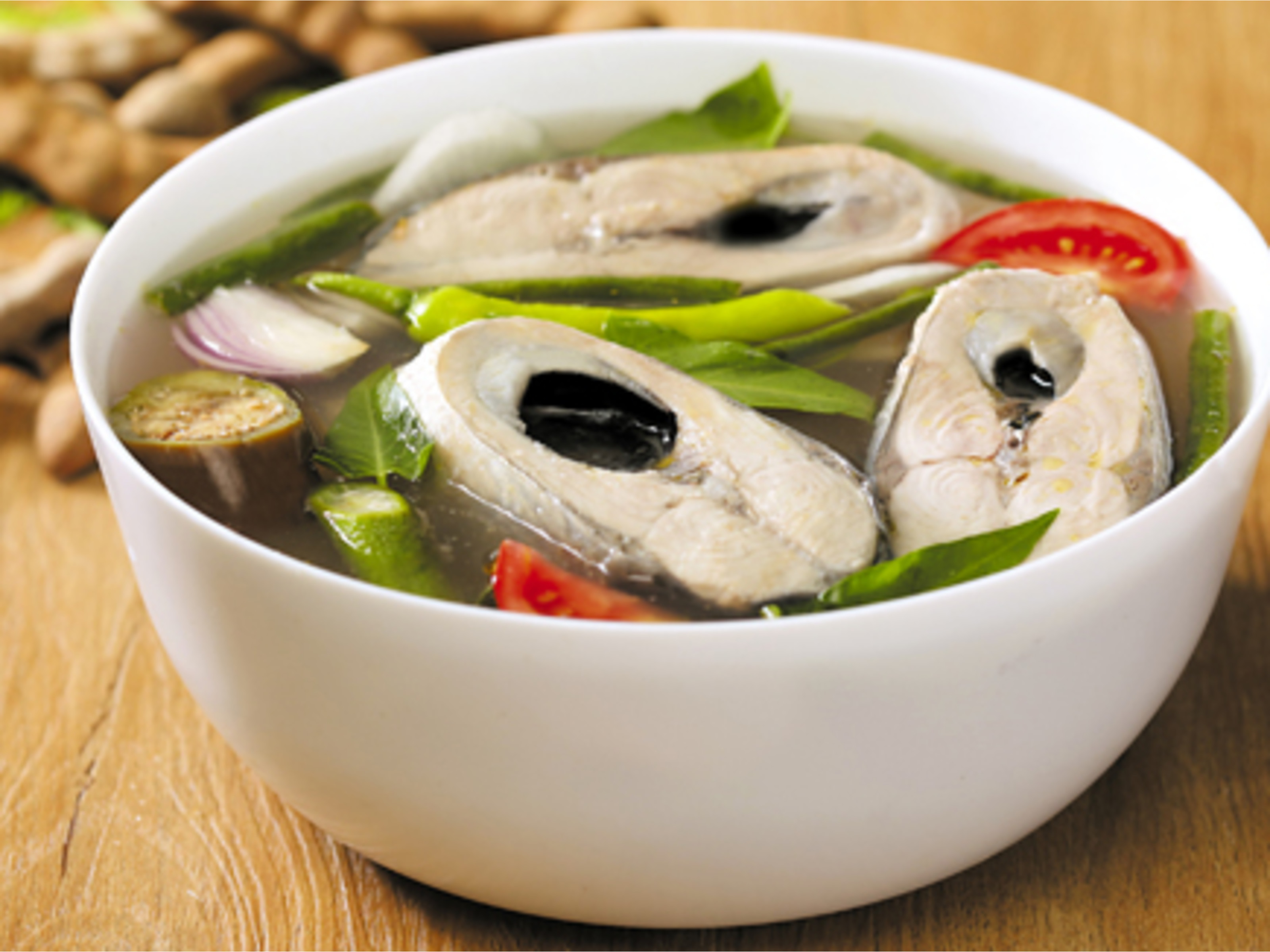 A bowl of fish sinigang, a popular Filipino sour and savory stew or soup, often using tamarind, tomatoes, or other souring agents.