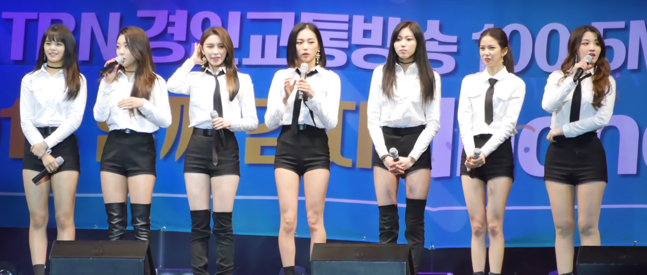 흰색 셔츠와 검은색 반바지를 입은 CLC 멤버들이 무대에 서 있다.