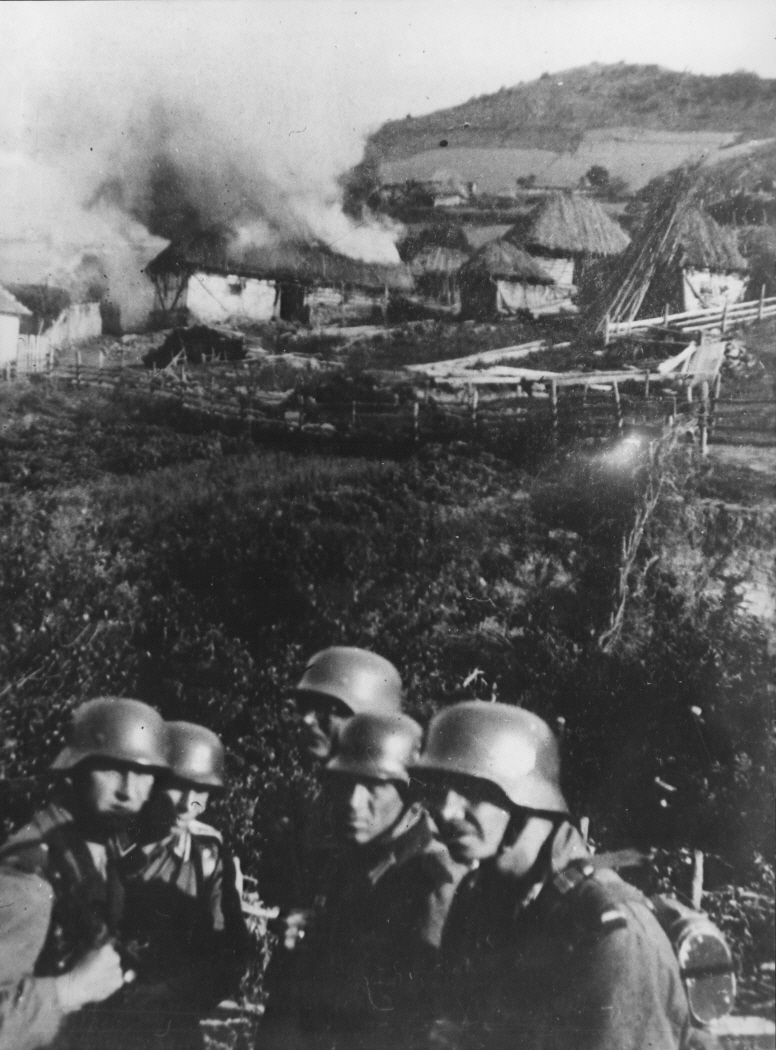 German soldiers setting fire to a Serbian village near Mitrovica, circa 1941, during World War II.