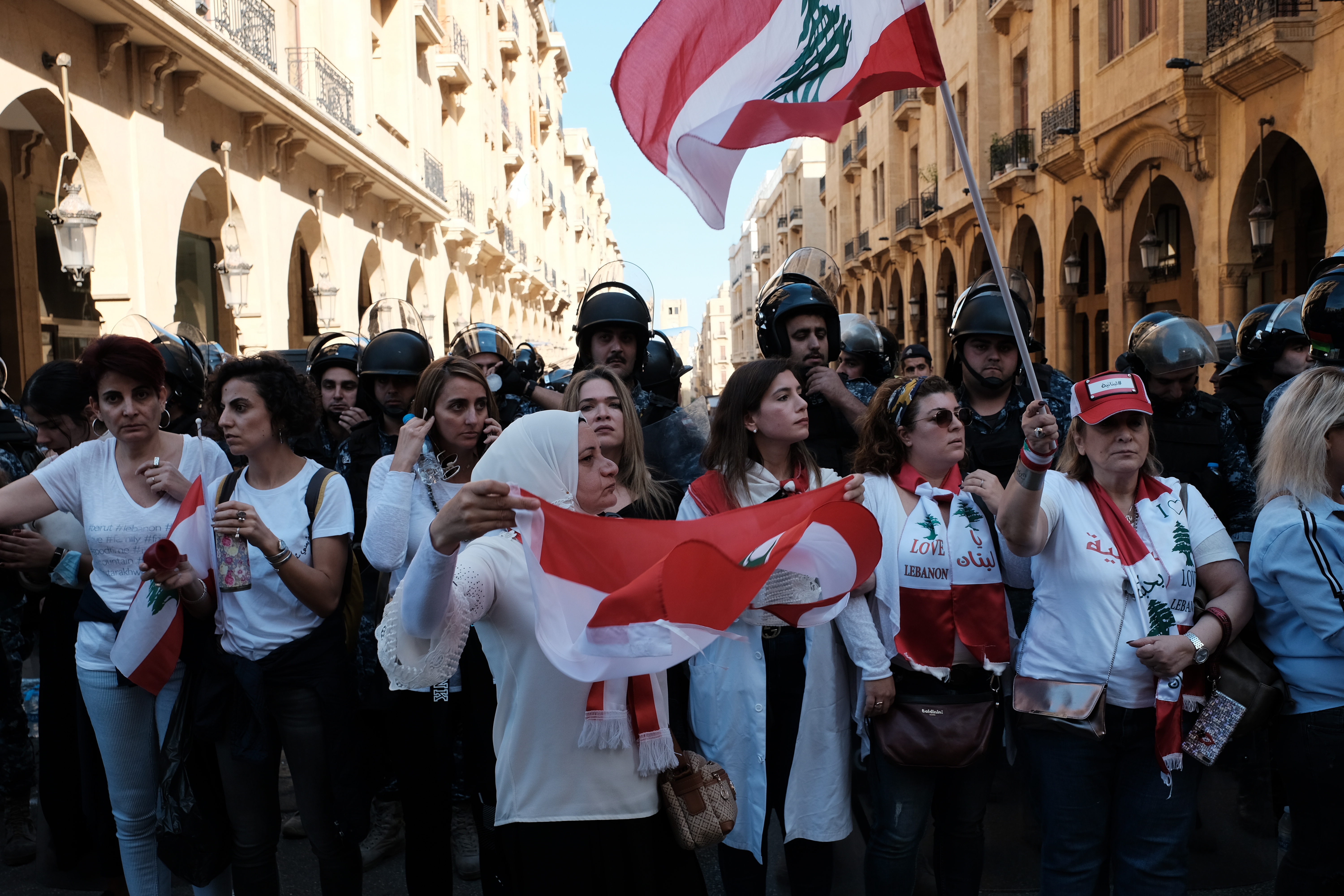 Para demonstran wanita membentuk barisan antara polisi anti huru-hara dan para demonstran di Riad el Solh, Beirut; 19 November 2019.