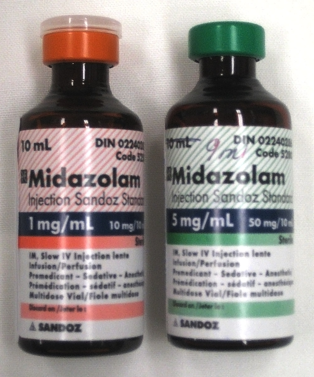 Midazolam 1 mg/mL과 5 mg/mL 라벨이 붙은 10 mL 병 두 개. 왼쪽 병은 빨간색 라벨에 1 mg/mL라고 적혀 있고, 오른쪽 병은 녹색 라벨에 5 mg/mL라고 적혀 있습니다. 두 병 모두 매우 작은 글씨로 인쇄되어 있습니다.