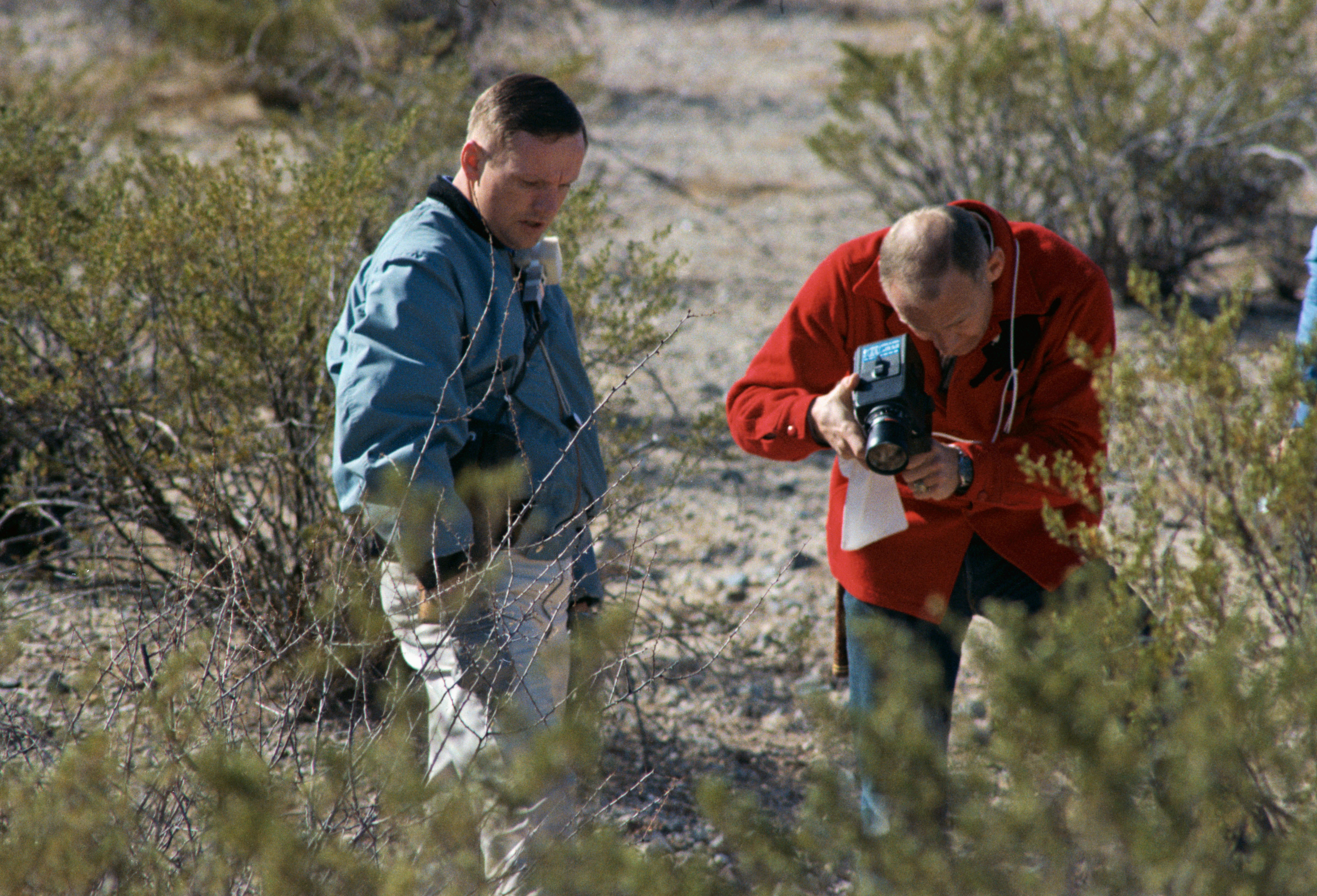 Aldrin photographs a geological specimen while Neil Armstrong looks on during training.