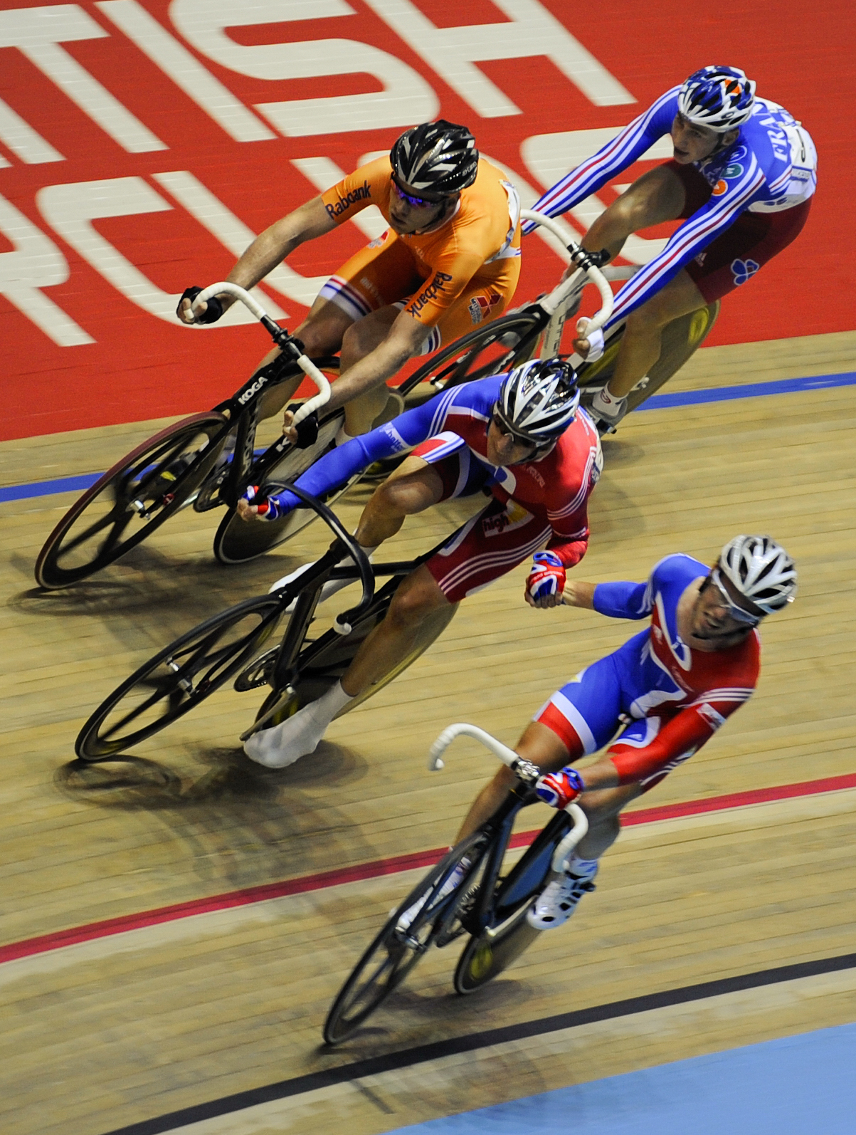 Cavendish passes a baton to Wiggins who is followed by two cyclists on the wooden track 