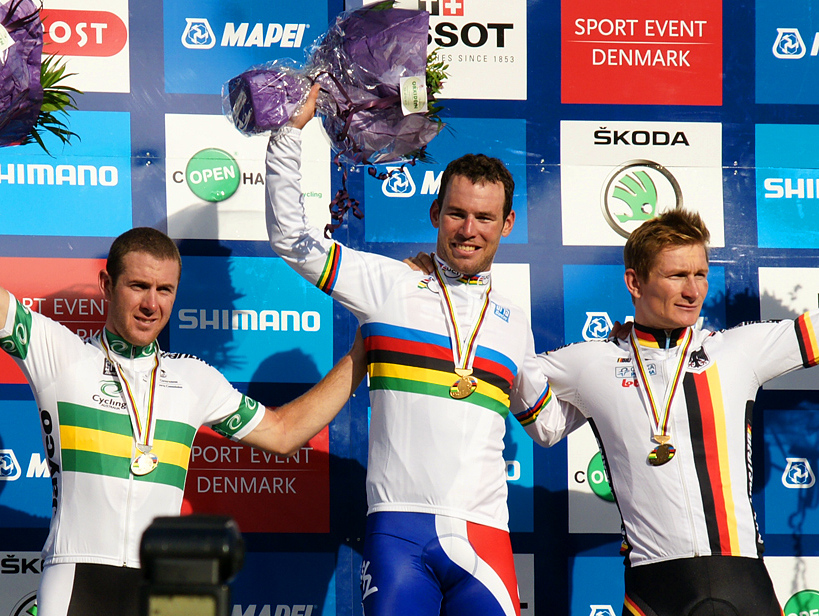 Three men on a podium celebrating with their arms raised 