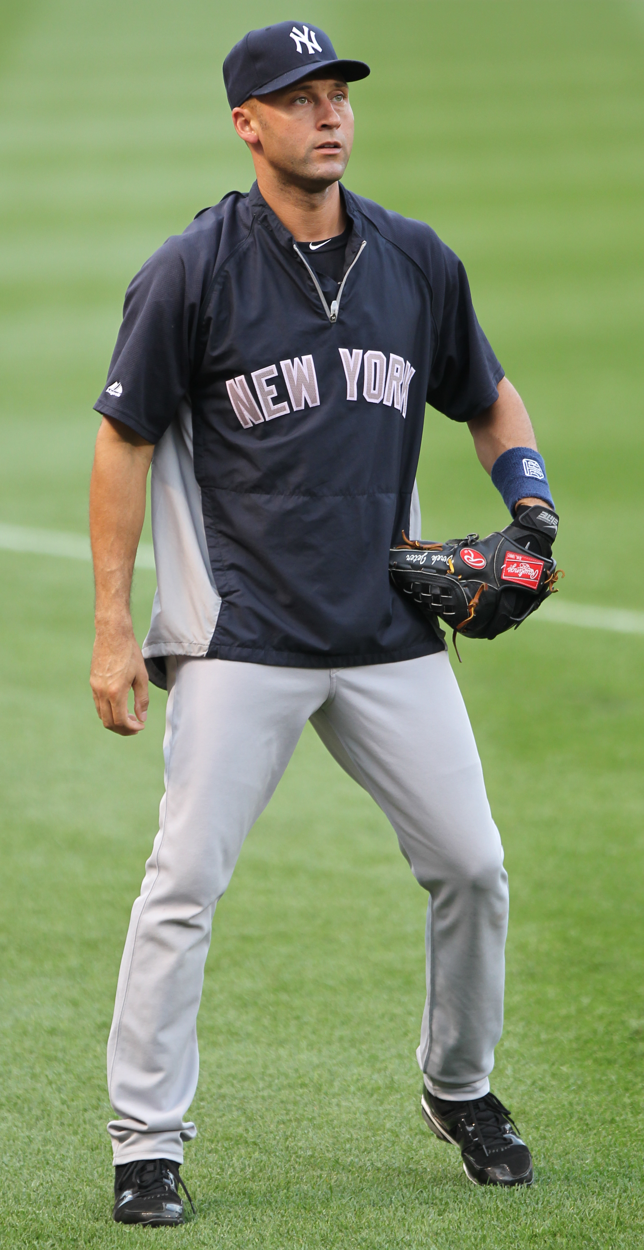 alt=A man in a navy windbreaker and navy hat prepares to catch a baseball.