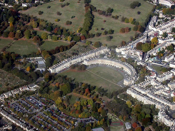앞과 왼쪽에 넓은 잔디밭이 있는 반원형 석조 건물 테라스의 항공 사진. 또한 주변 건물 테라스도 보여준다.