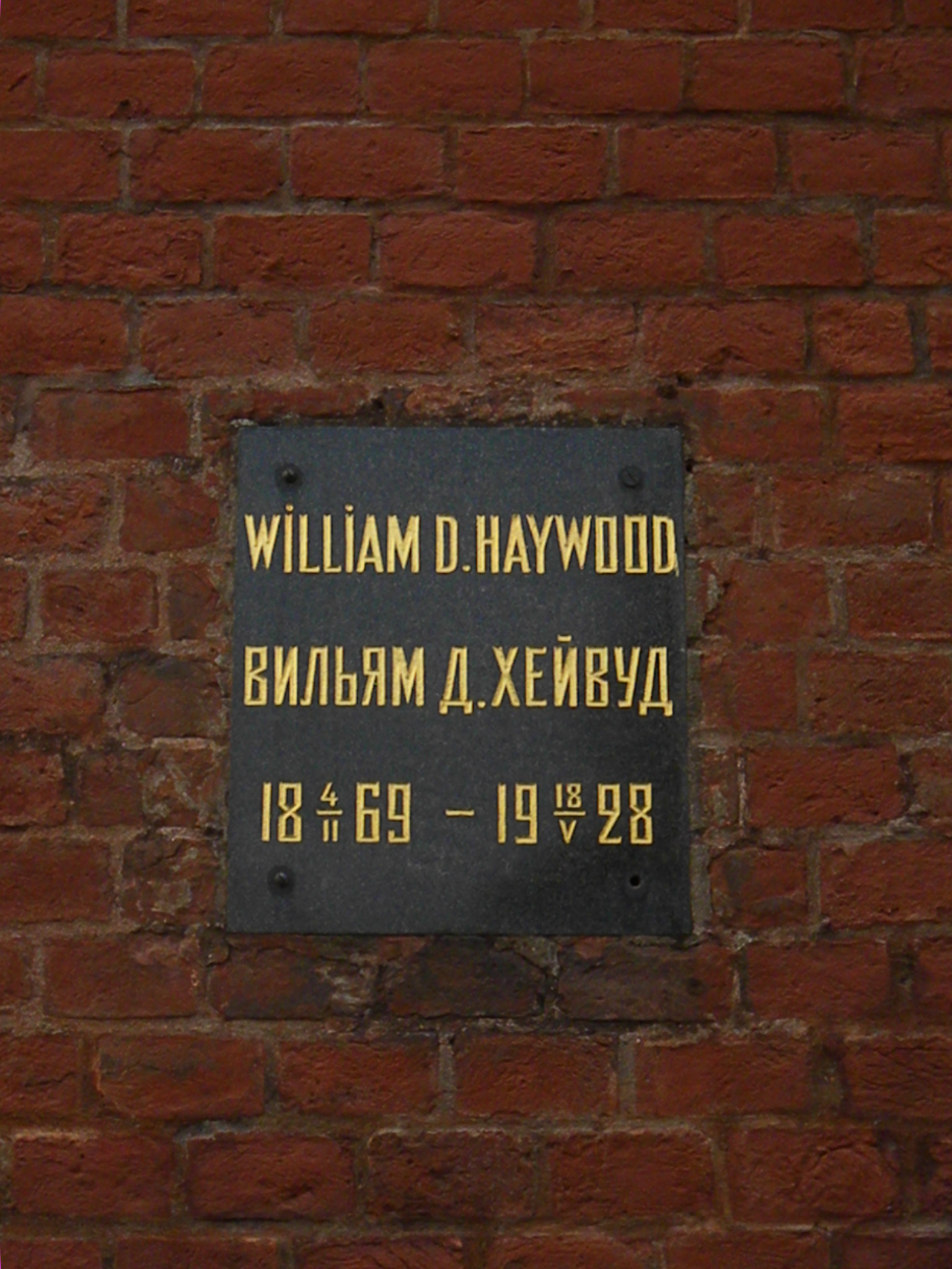 Plaque on a brick wall with inscription: William D. Haywood/Вильям Д. Хейвуд, 1869-02-04–1928-05-18