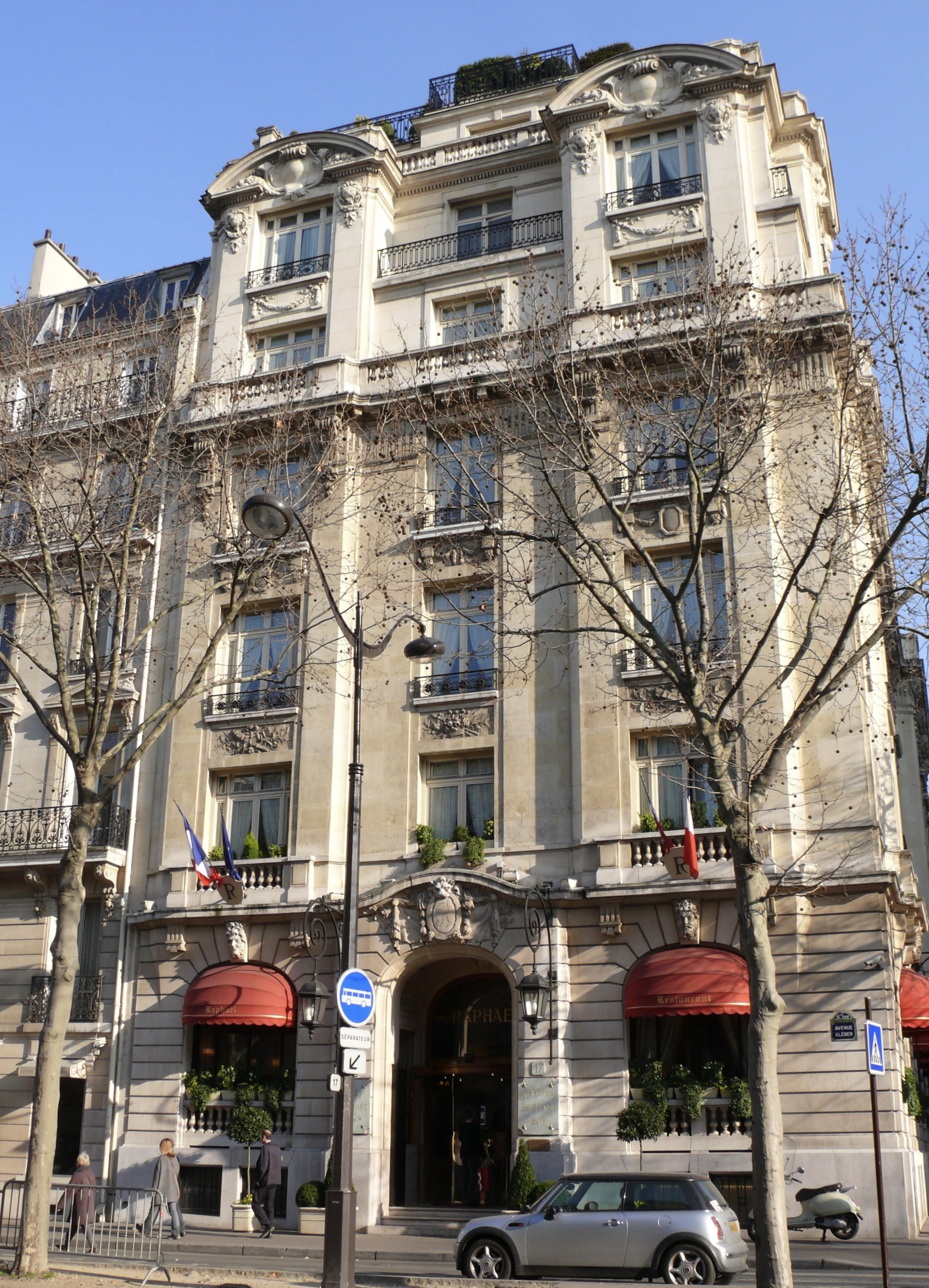 A six-storey building at the corner of a terrace lined in front by bare trees