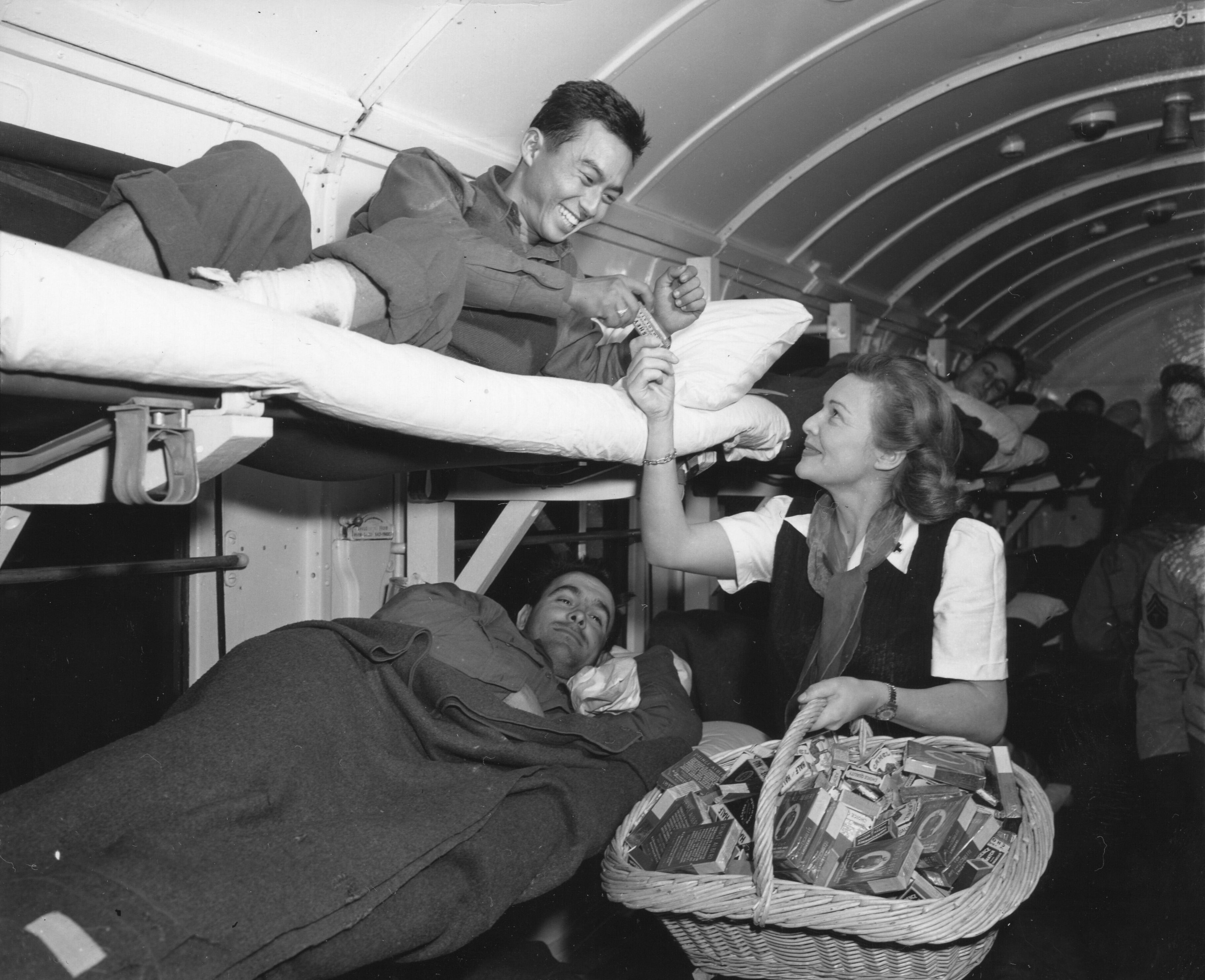 1944년 11월 1일, 프랑스 돔페어 지역에서 부상당한 일본계 미국인 병사에게 담배를 건네는 캐럴.