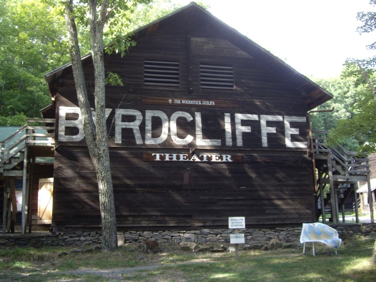 돌로 된 기단을 가진 나무 건물, 측면 전체에 큰 글자로 Byrdcliffe가 칠해져 있고, 그 아래에 작은 글자로 Theater가 적혀 있습니다.