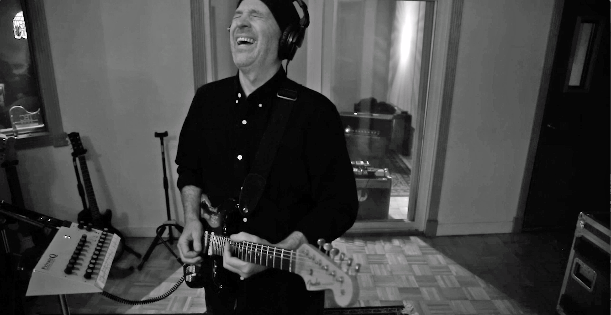 A black and white photo of an older man playing guitar