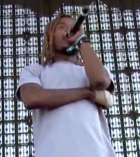 한 남자가 무대에서 마이크에 대고 랩을 하고 있다.