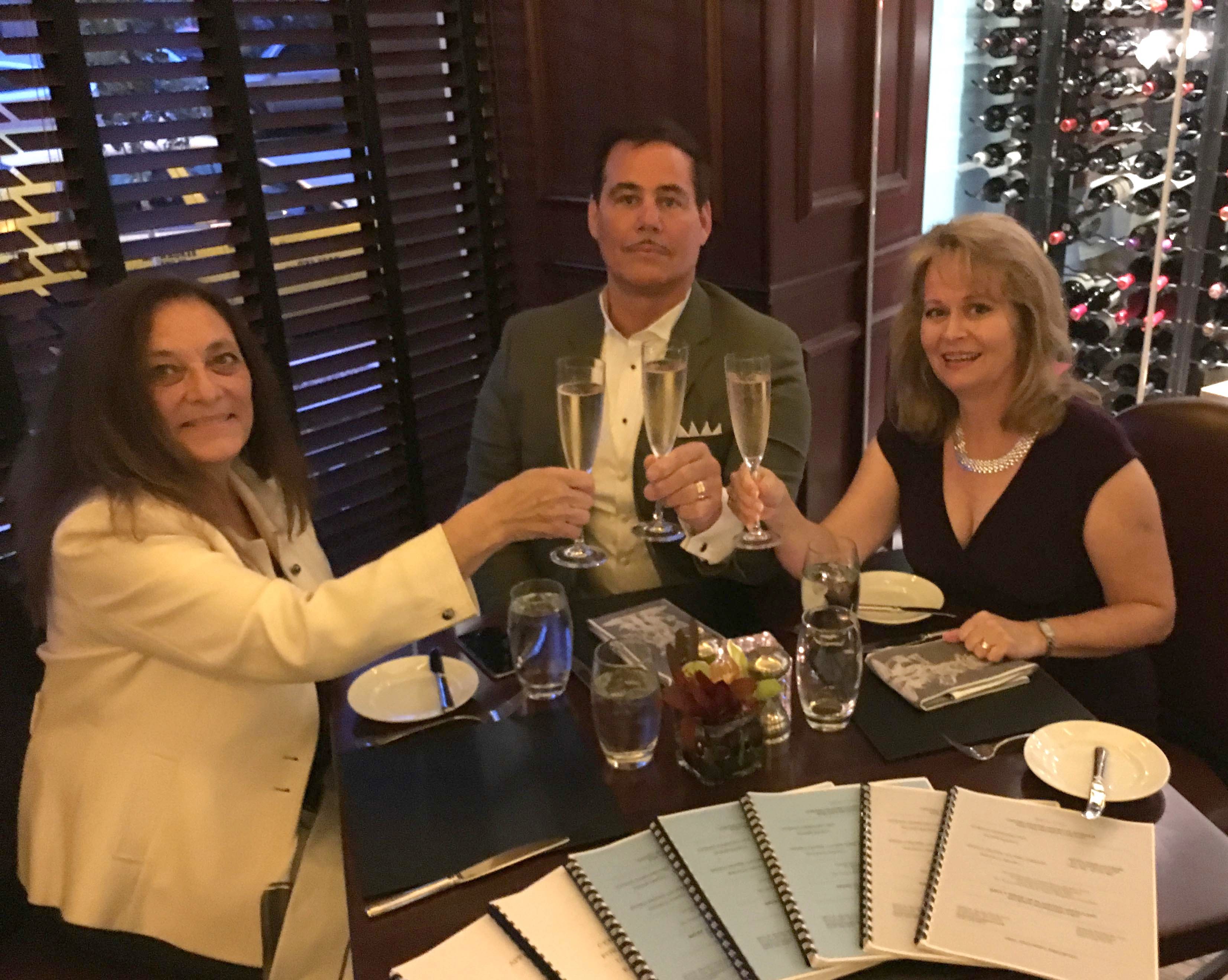 닥터 에드워드 A. 그라프 박사, 변호사 리아 풀로스-뮐러 (미국 올림픽 선수이자 세계 기록 보유자), 그리고 변호사이자 작가인 수잔 스위프트가 위스콘신주 밀워키의 피스터 호텔에서 미국 지방법원의 미국 증권거래위원회 규정 위반 주장 기각 항소 결정 및 미국 제7순회 항소법원의 파기 환송 결정 이후 축하하는 모습.