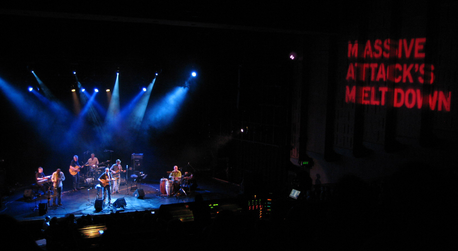 칼리어와 그의 밴드가 무대 위에서 찍은 사진으로, 옆에는 대형 매시브 어택 배너가 있다