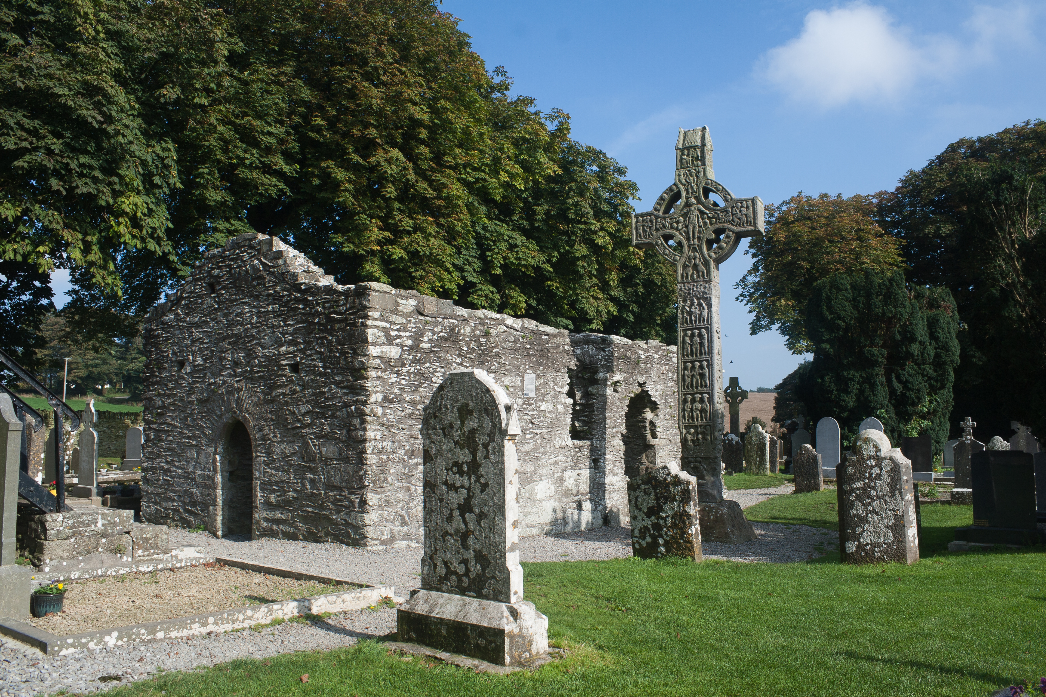 Reruntuhan Monasterboice di County Louth, menampilkan salib tinggi dan menara bundar, contoh arsitektur Kristen awal Irlandia.