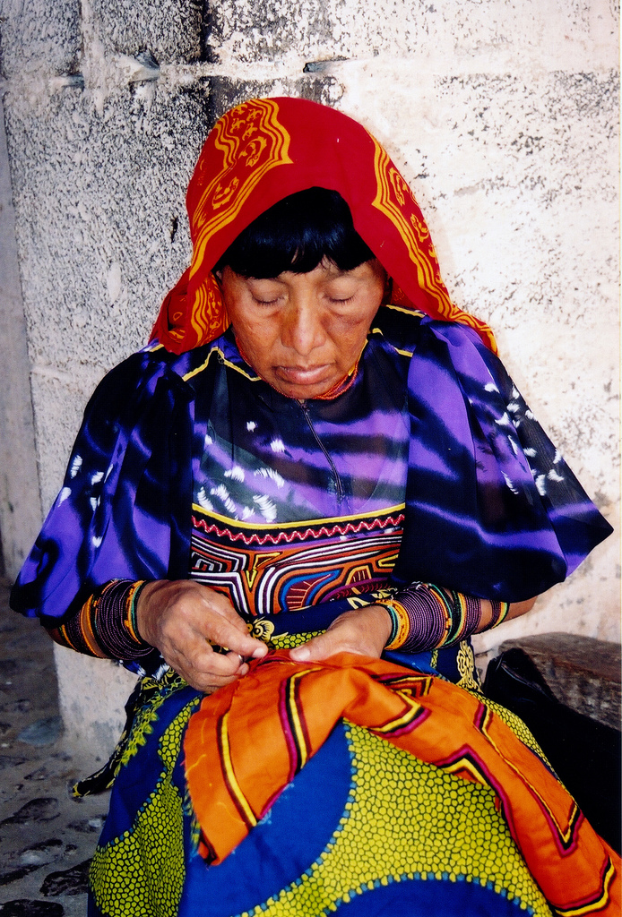 A Guna woman engaged in sewing a mola, a distinctive textile art form of the Guna people.