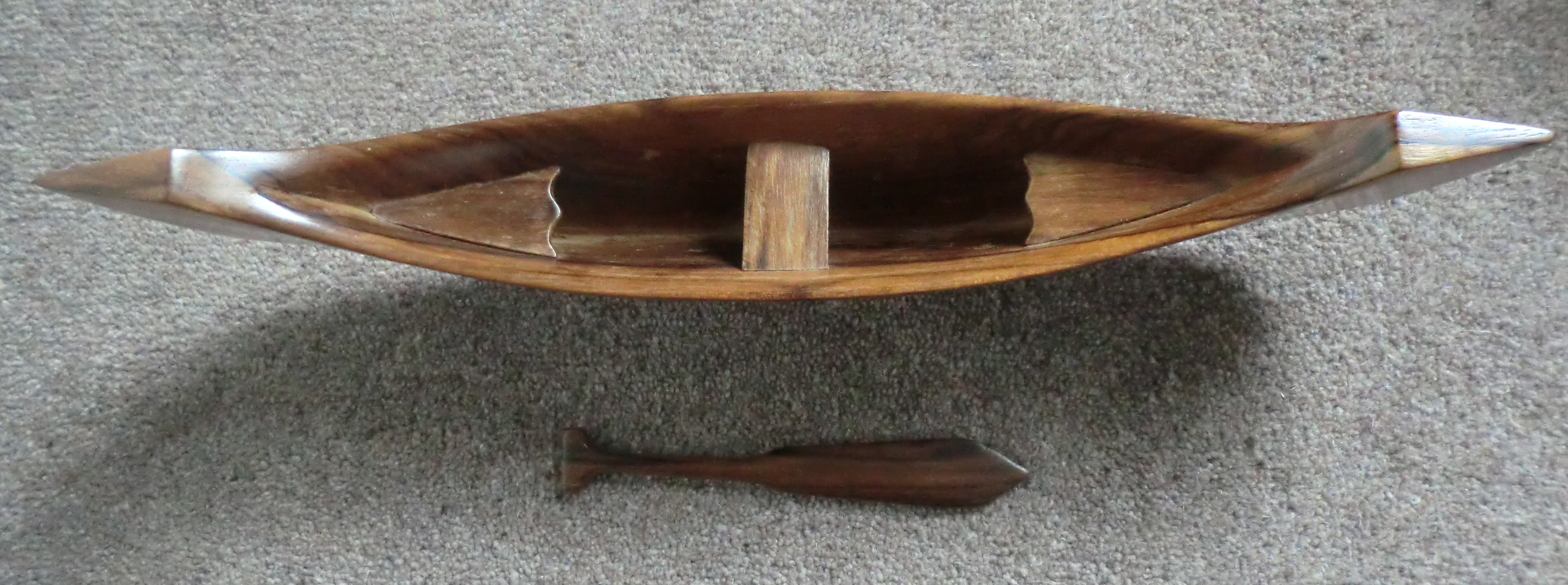 Miniatur perahu panjang berukir, melambangkan tradisi maritim.