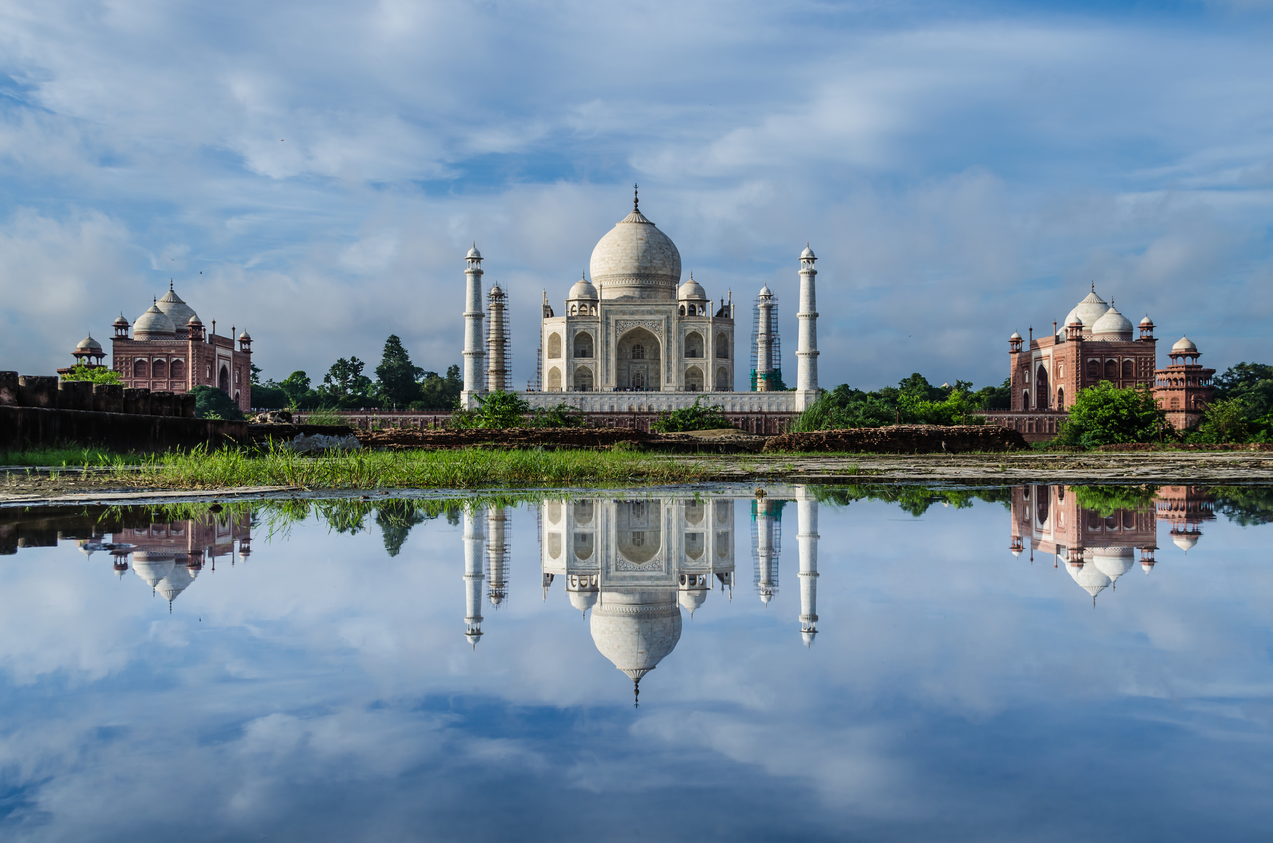 The Taj Mahal from across the Yamuna River showing two outlying red sandstone buildings, a mosque on the right (west) and a jawab (response) built for architectural balance, exemplifying Mughal symmetry and aesthetic perfection.