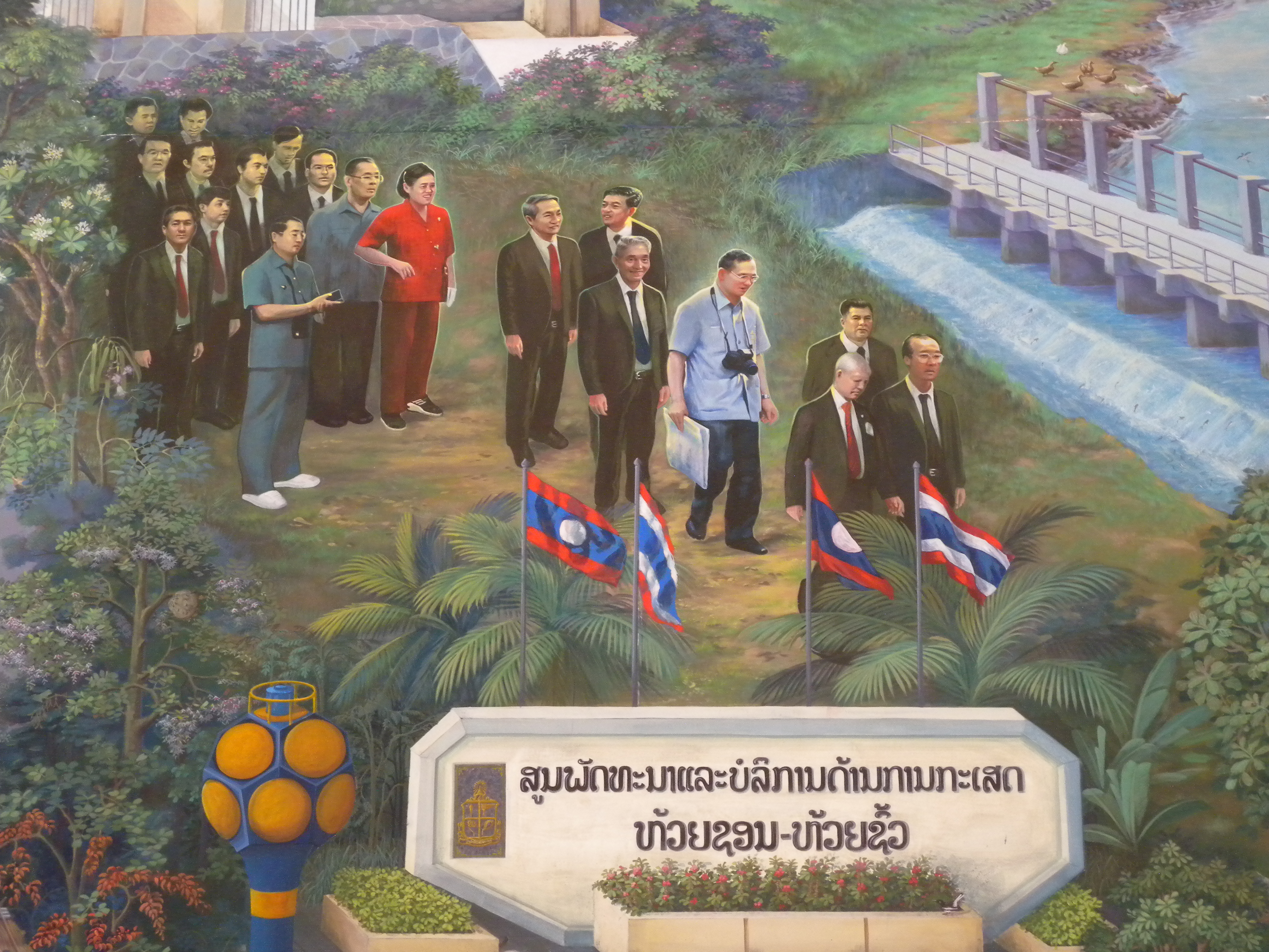 จิตรกรรมฝาผนังแสดงความสัมพันธ์ไทย-ลาว: พระบาทสมเด็จพระมหาภูมิพลอดุลยเดชมหาราช บรมนาถบพิตร และหนูฮัก พูมสะหวัน ประธานประเทศลาว เสด็จฯ เปิดศูนย์พัฒนาและบริการด้านการเกษตรห้วยซอน-ห้วยซั้ว นครหลวงเวียงจันทน์ วันที่ 8 เมษายน ค.ศ. 1994